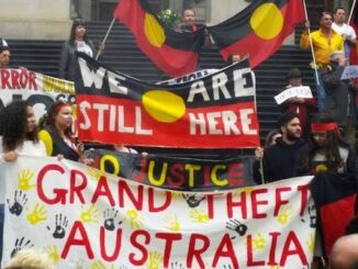 Protesters with Indigenous Australian flags and banners.