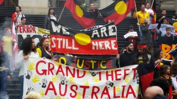 Protesters with Indigenous Australian flags and banners.