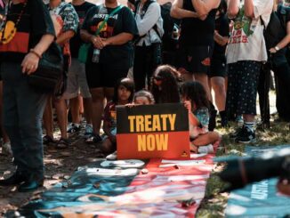 People gathered holding a "Treaty Now" sign.