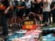 People gathered holding a "Treaty Now" sign.