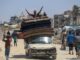 Man on car with stacked mattresses, cheering.
