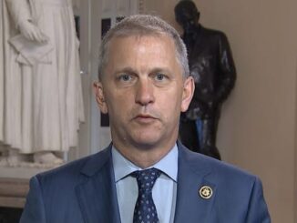 Man in suit with statues in background.