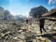 People walking through urban rubble and debris.