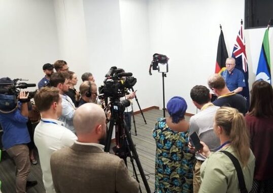 Press conference with multiple cameras and people.