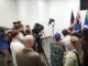 Press conference with multiple cameras and people.