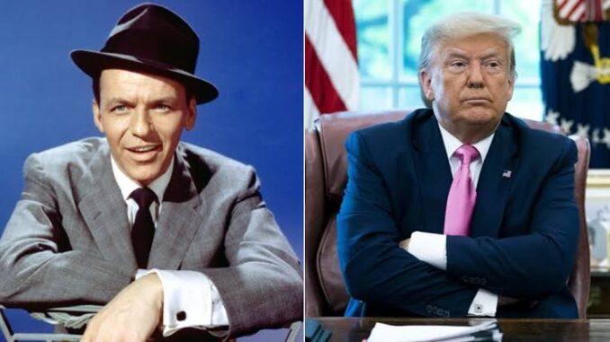 Two men sitting, one in suit, hat.