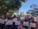 Protesters holding "Raise the Rate" signs outdoors.