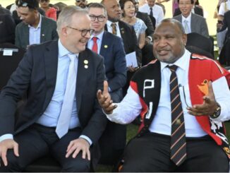 Two men seated, talking at an event.