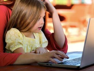 Child and adult using a laptop together.