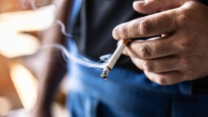 Thumb and forefinger clasp lit cigarette Thumb and forefinger clasp lit cigarette