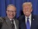 Two men smiling in suits and ties.