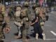 Soldiers detaining person during street protest.