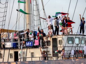 People waving flags aboard a large ship.