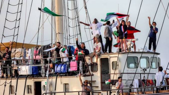 People waving flags aboard a large ship.