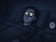 Person wide awake in bed at night.