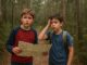 Two boys with map in forest.