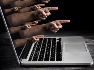 Hands pointing out of a laptop screen.