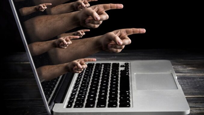 Hands pointing out of a laptop screen.
