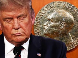 Man in suit beside Nobel Prize medallion.