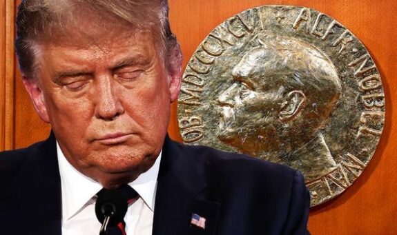 Man in suit beside Nobel Prize medallion.