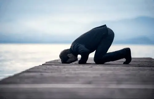 Person kneeling on dock by the water.