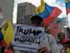 Protesters holding signs and Venezuelan flags.