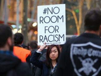Protester holding "No Room for Racism" sign.