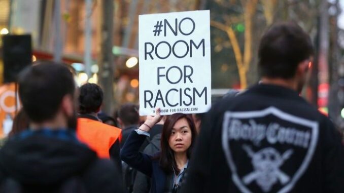 Protester holding "No Room for Racism" sign. Protester holding "No Room for Racism" sign.