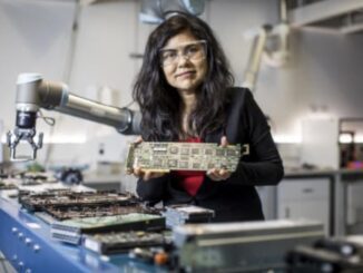 Woman holding circuit board in a laboratory.