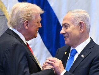 Two men shaking hands in front of flags.