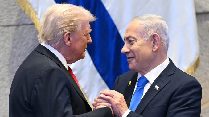 Two men shaking hands in front of flags.