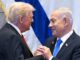 Two men shaking hands in front of flags.