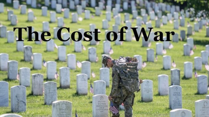 Soldier in cemetery with "The Cost of War. Soldier in cemetery with "The Cost of War.