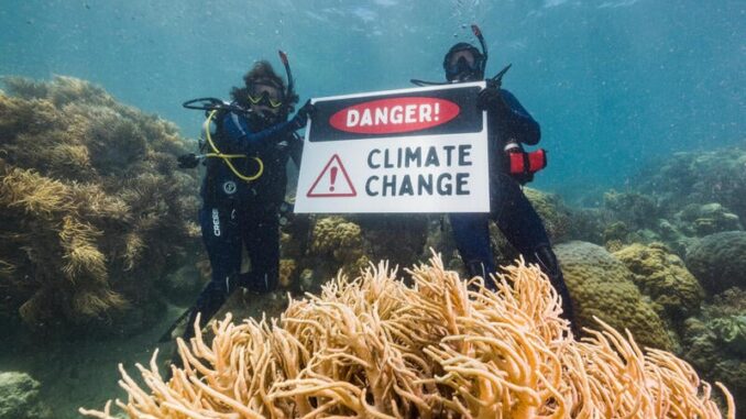 Divers hold "Danger! Climate Change" sign underwater. Divers hold "Danger! Climate Change" sign underwater.