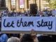 Protesters holding "let them stay" sign.