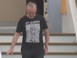Man in Joy Division shirt on stairs.
