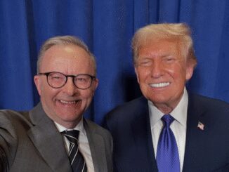 Two men smiling in front of curtain.
