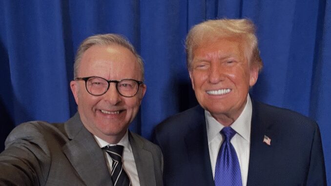 Two men smiling in front of curtain.