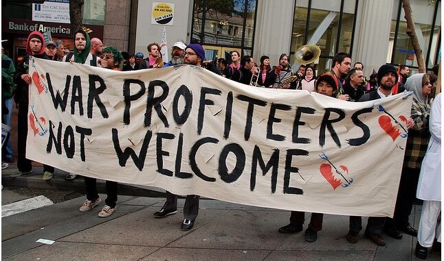 Protesters holding "War Profiteers Not Welcome" banner.