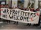 Protesters holding "War Profiteers Not Welcome" banner.