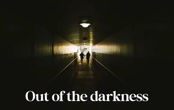 Silhouettes walking towards light in tunnel.