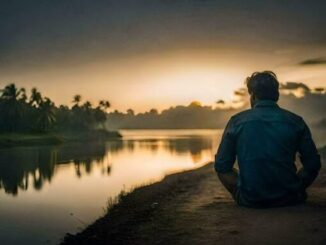Man sitting by a river at sunset.