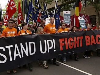 Protesters holding "Stand Up! Fight Back!" banner.