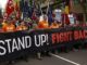 Protesters holding "Stand Up! Fight Back!" banner.