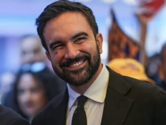 Bearded man in dark suit smiling at gathering