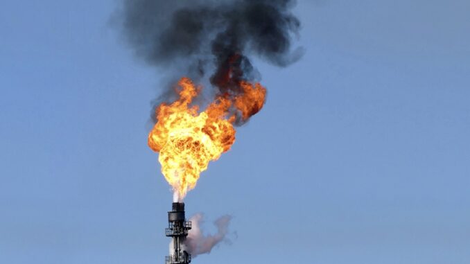 Industrial gas flare with black smoke.