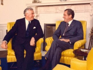 Two men seated in yellow chairs, conversing.