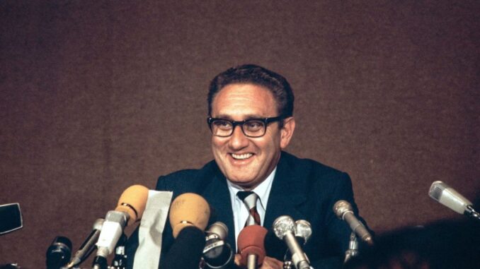 Smiling man speaking at a press conference.