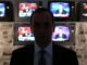 Silhouette of man in front of televisions.