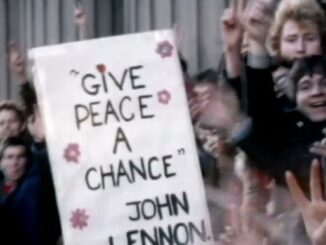 Crowd holding "Give Peace a Chance" sign.